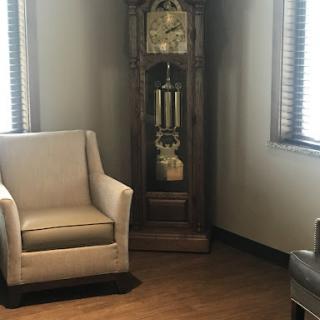 A cozy corner featuring a stylish armchair and an elegant grandfather clock, illuminated by natural light.