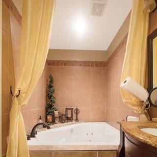 A cozy bathroom with a bathtub surrounded by curtains and warm lighting.