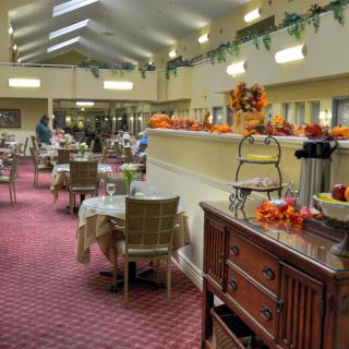 A cozy dining room adorned with autumn decorations, featuring neatly arranged tables and chairs.
