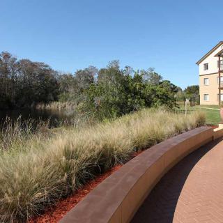 A serene landscape featuring a building, lush greenery, and a winding pathway.