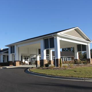 A modern hotel entrance with a spacious driveway and clear blue sky.