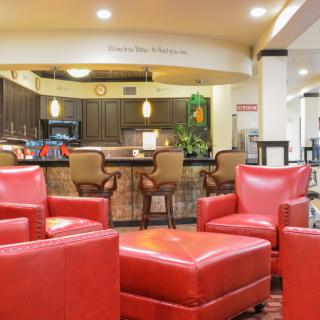 A modern lobby with red chairs and a bar area in the background.