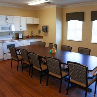 A kitchen and dining area with a long table and multiple chairs, suitable for meetings.