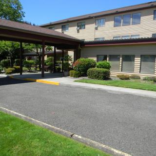 Exterior view of a building with a covered entrance and landscaped surroundings.
