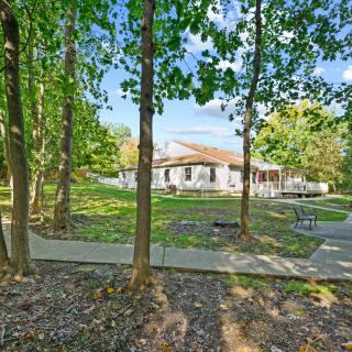 A residential house surrounded by trees with a pathway in the foreground.