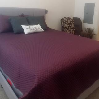 A neatly made bed with a burgundy blanket and decorative pillows.