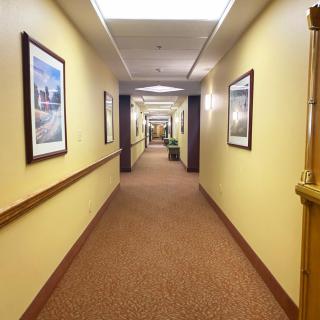 A well-lit hotel hallway with framed artwork on the walls and carpeted flooring.