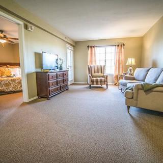 A cozy living room with a sofa, television, and ample natural light.