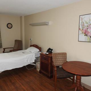 A hospital room featuring a bed, table, and chairs with medical equipment.