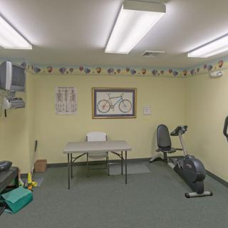 A small exercise room with gym equipment and a bicycle-themed decoration on the wall.