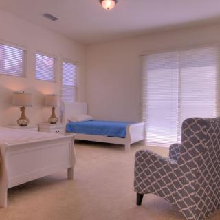 A spacious bedroom with two beds, an armchair, and soft lighting from table lamps.