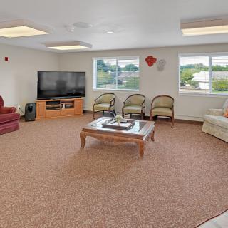 A spacious living room with a large television, sofas, chairs, and a coffee table.
