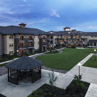 A residential apartment complex with a well-maintained courtyard and gazebo under an evening sky.