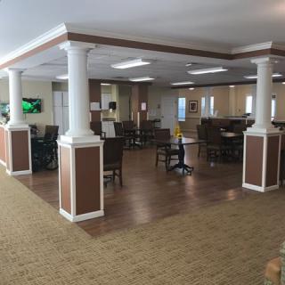 A spacious dining area with columns, tables, and chairs on wood flooring.