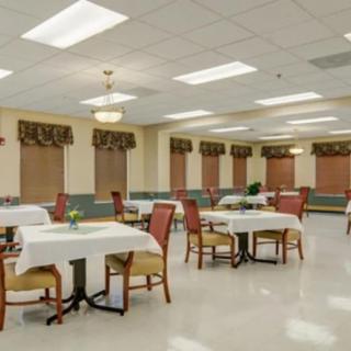An empty dining room with neatly arranged tables and chairs under bright lighting.