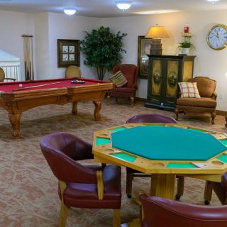 A cozy game room featuring a poker table and a pool table, with comfortable seating for relaxation.