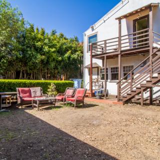 A spacious backyard featuring outdoor seating and a wooden deck with stairs.