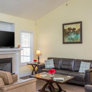 A cozy living room featuring a sofa, coffee table, fireplace, and a mounted TV.