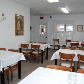 A simple and clean dining area with tables and chairs, waiting for patrons.