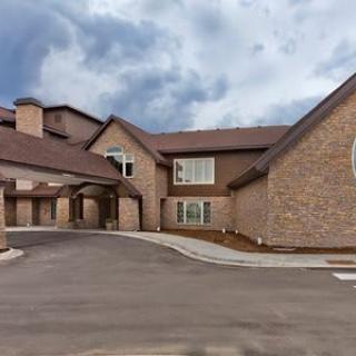 A large brick residential building with a driveway under a cloudy sky.