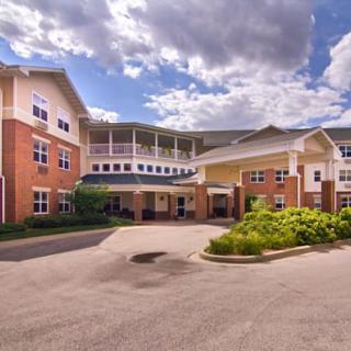 A large residential building with a landscaped entrance under a cloudy sky.