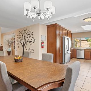 A modern open-concept dining and kitchen area featuring a wooden table, upholstered chairs, and a decorative wall mural.