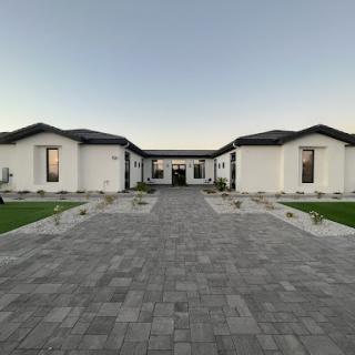 A beautifully designed modern home surrounded by well-maintained landscaping and a spacious paved driveway.