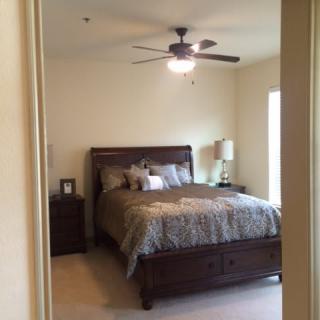 A cozy bedroom with a double bed, decorated with pillows, bedside tables, and a ceiling fan.