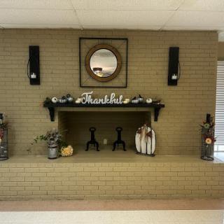 A cozy fireplace adorned with seasonal decorations and a mirror above.