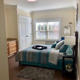 A cozy bedroom with a neatly made bed, decorative pillows, and a soft rug.