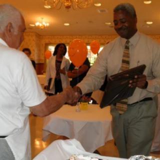 Two individuals shaking hands during an award ceremony.