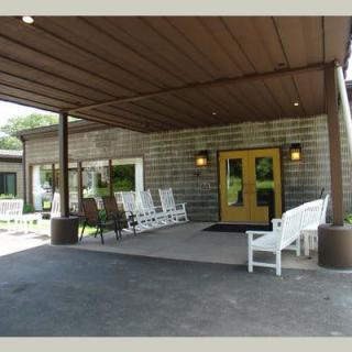 A covered building entrance with several rocking chairs for outdoor seating.