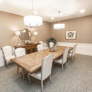 Elegant dining room with a wooden table and upholstered chairs, featuring chandeliers and stylish decor.