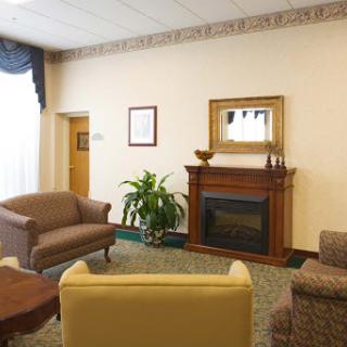 A cozy living room featuring comfortable seating, a wooden fireplace, and decorative elements.