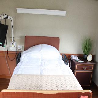 A hospital patient room featuring a bed, bedside table, and medical equipment.