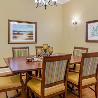 A cozy dining room with a wooden table and upholstered chairs, adorned with wall art and ambient lighting.