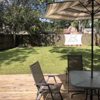 A sunny backyard with a wooden deck and patio furniture under an umbrella.