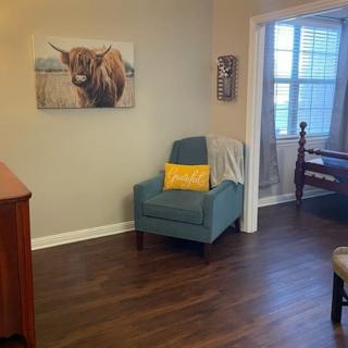 A cozy living room corner with an armchair and artwork on the wall.