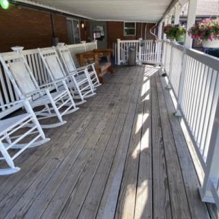 A peaceful covered porch with white rocking chairs and hanging flower baskets.