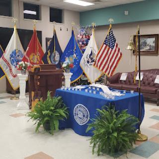 A setup for a formal ceremony featuring various military flags and a podium.