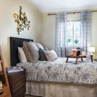 A cozy bedroom with a neatly made bed, decorated pillows, and soft lighting.