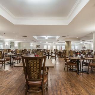 A spacious dining room with neatly arranged tables and chairs on a hardwood floor.