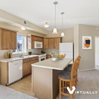 A modern kitchen with wooden cabinets, an island counter, and contemporary lighting.