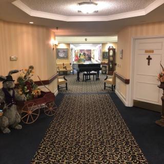 A hallway with elegant decor featuring a piano and floral arrangements.