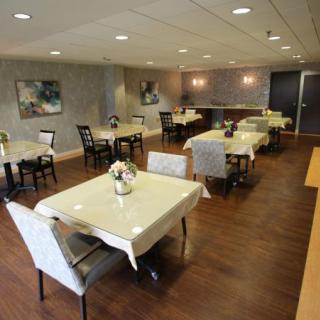 An elegant dining room with several neatly arranged tables and chairs, adorned with simple decor and soft lighting.