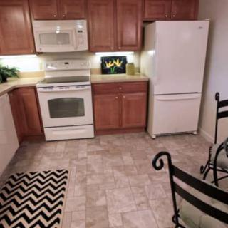 A modern kitchen with wooden cabinets, white appliances, and tiled flooring.