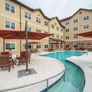 A hotel with a swimming pool and outdoor seating under umbrellas.