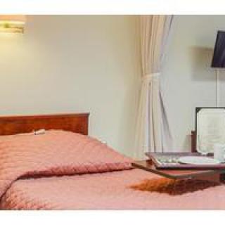 A cozy bedroom with a neatly made bed, a wall lamp, and a tray on the bed.