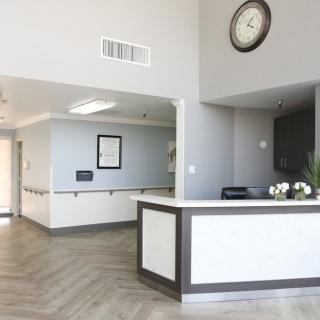 A modern and minimalist reception area with a desk, wall clock, and a clean design.