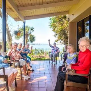 A group of seniors enjoying a sunny day on a patio with an ocean view.